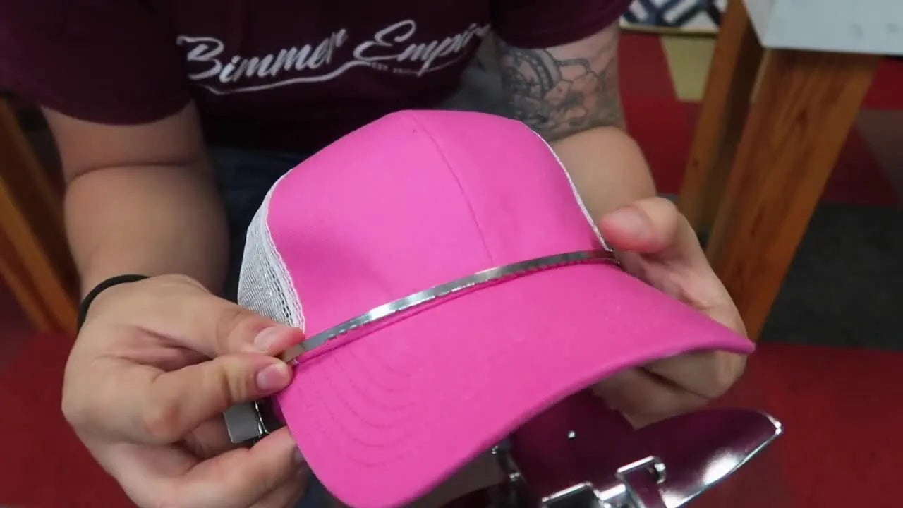 A close-up of the cap clamp’s red alignment line perfectly centered on the hat’s front seam for accurate cap embroidery placement.
