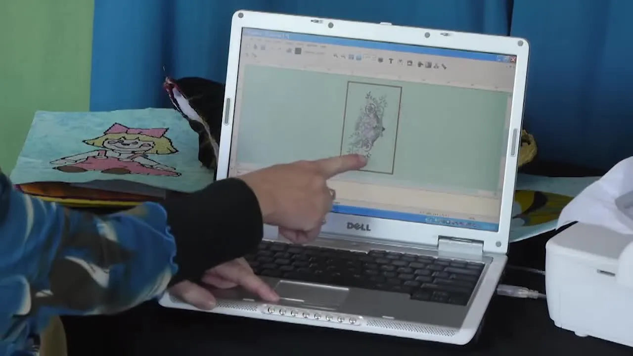 A laptop screen shows the Singer Futura software rotation handle and design outline used to position a motif precisely before multi-hooping.