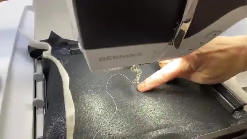 A close-up of the Bernina 790 Pro laser dot marking the exact needle landing point on dark fabric before stitching begins.
