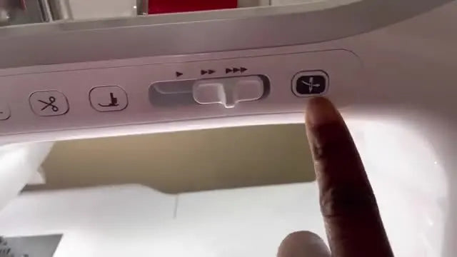 A close-up of a finger pressing the Brother Stellaire automatic needle threader button on the machine’s control panel.