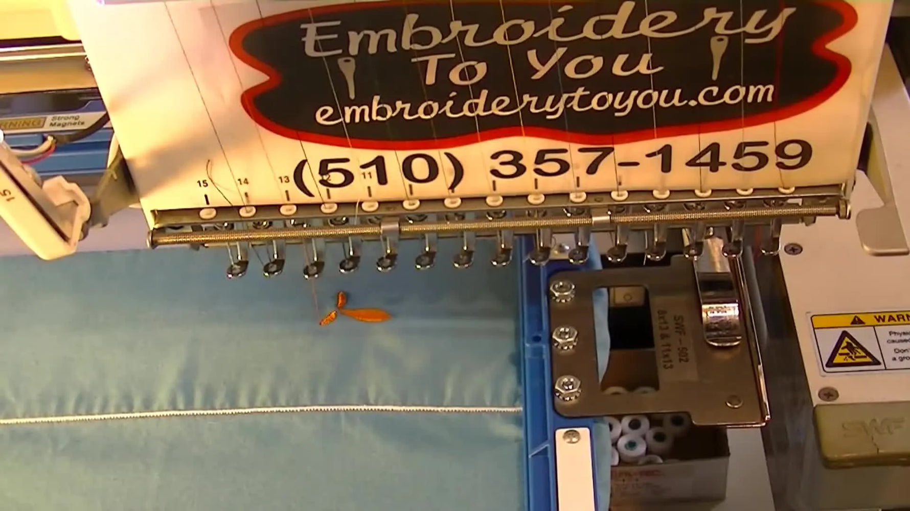A close-up of a magnetic Mighty Hoop clamping a blue pillowcase hem flat and secure for embroidery.