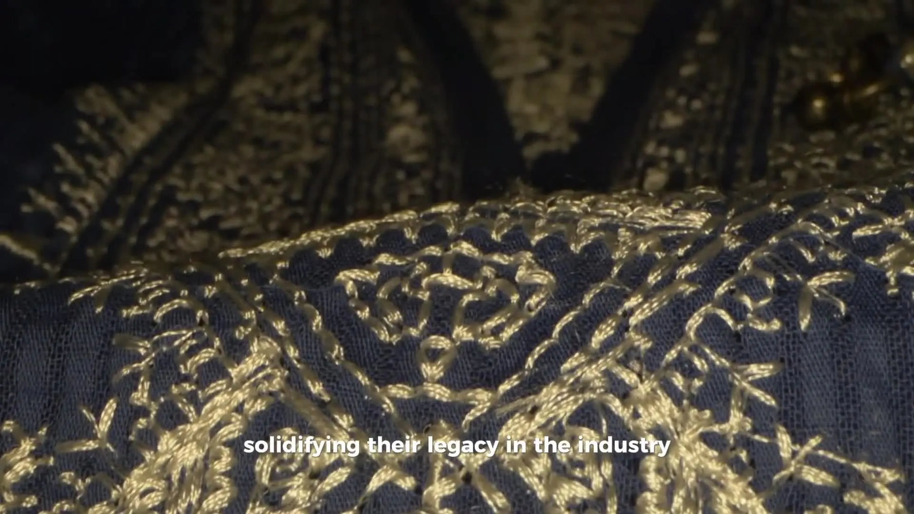 A macro close-up of dense gold embroidery on dark blue fabric, highlighting clean stitch definition and premium texture.