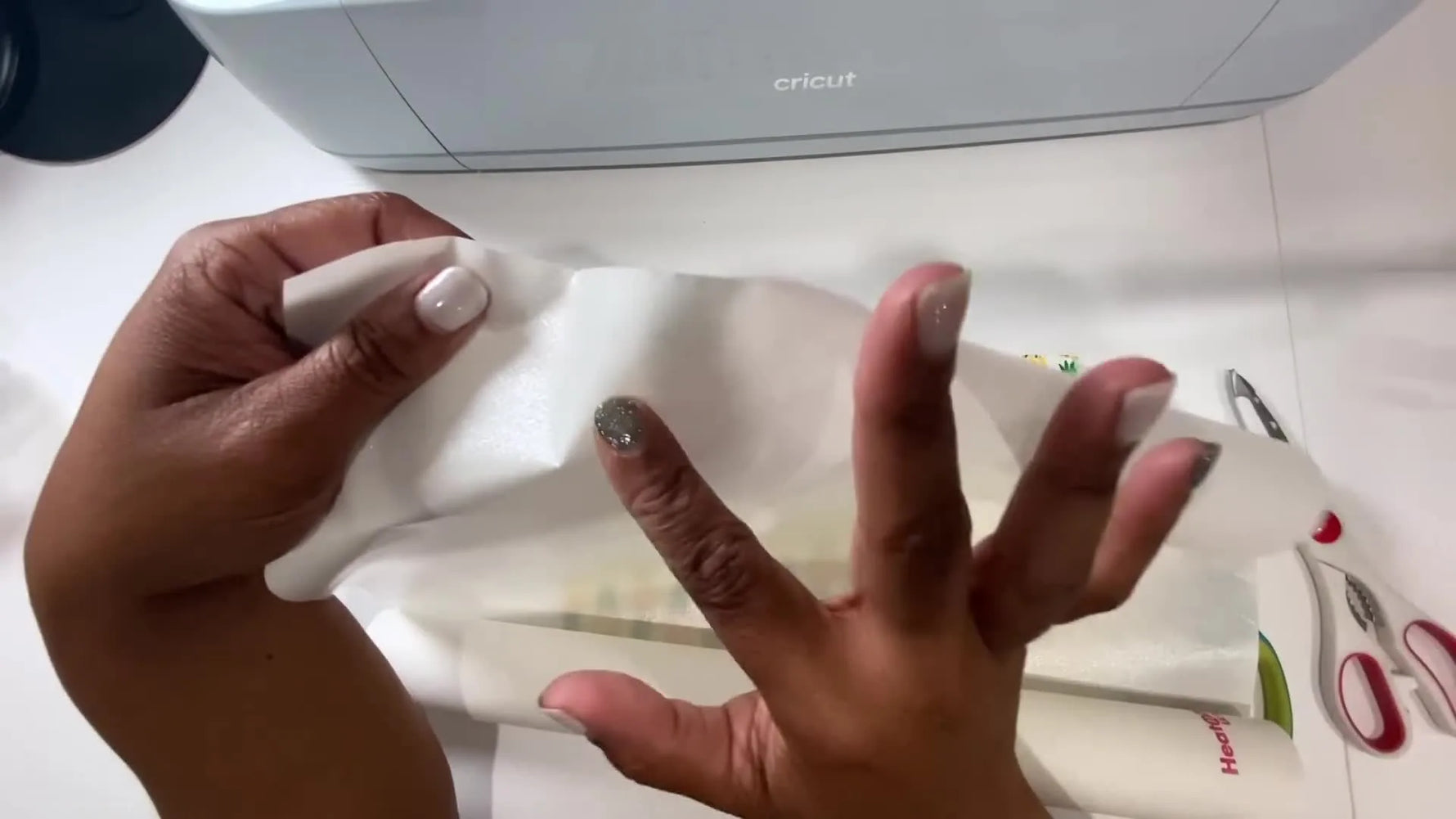 A heat press clamps down on a fabric-and-HeatnBond sandwich protected by parchment paper, capturing the exact moment that makes Cricut-cut appliqué reliable.
