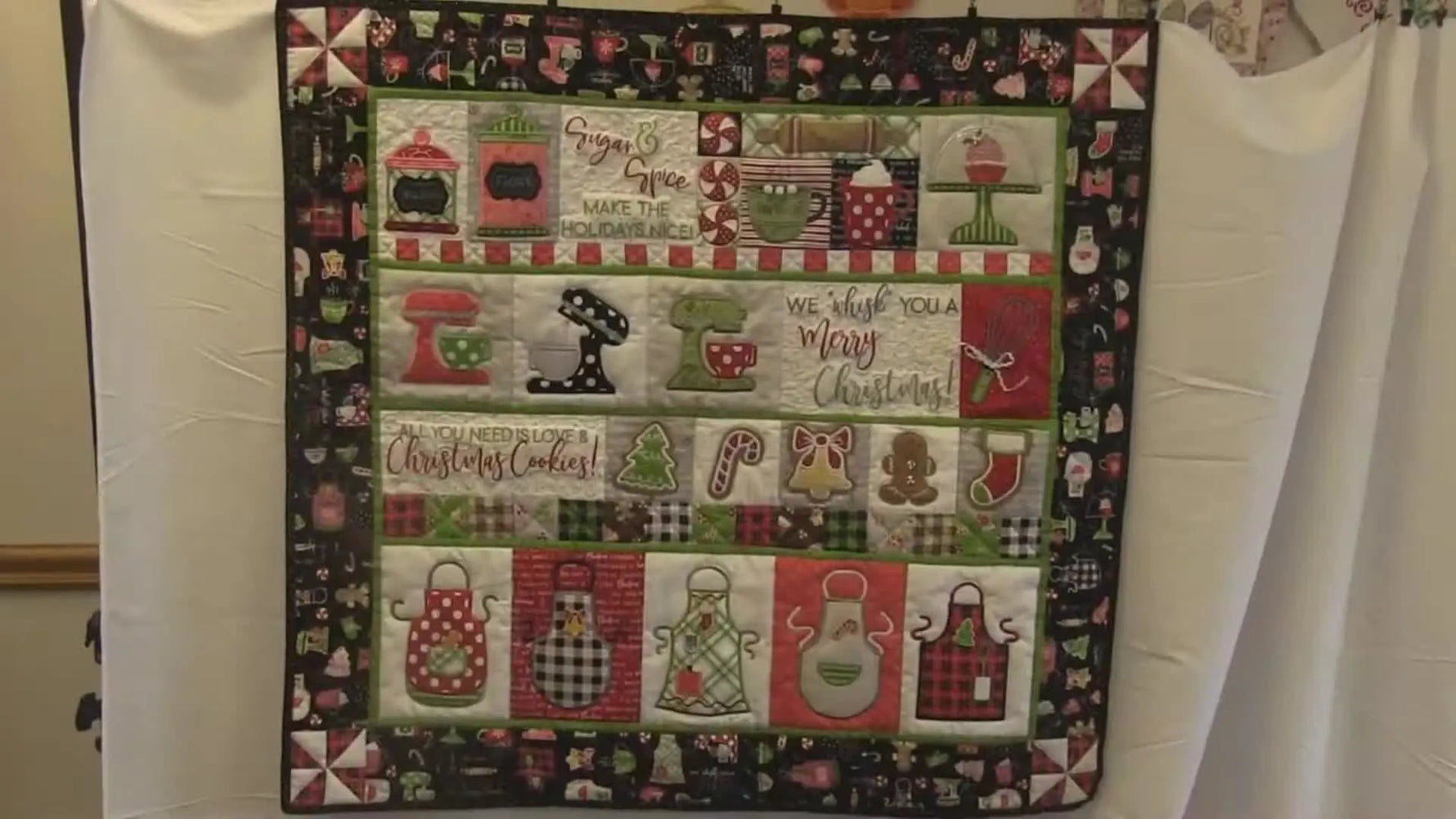 A full, wide view of the finished “We Whisk You a Merry Christmas” hanging quilt showing the complete block layout and mixed-media details.