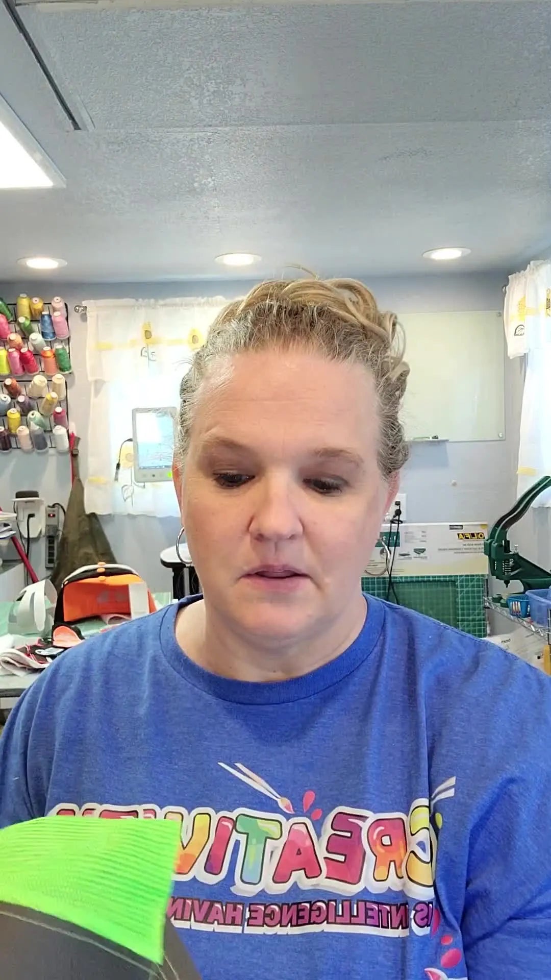 A close-up of the presenter holding a Richardson 112 trucker hat, highlighting the cap style that most often causes needle breaks and machine errors.