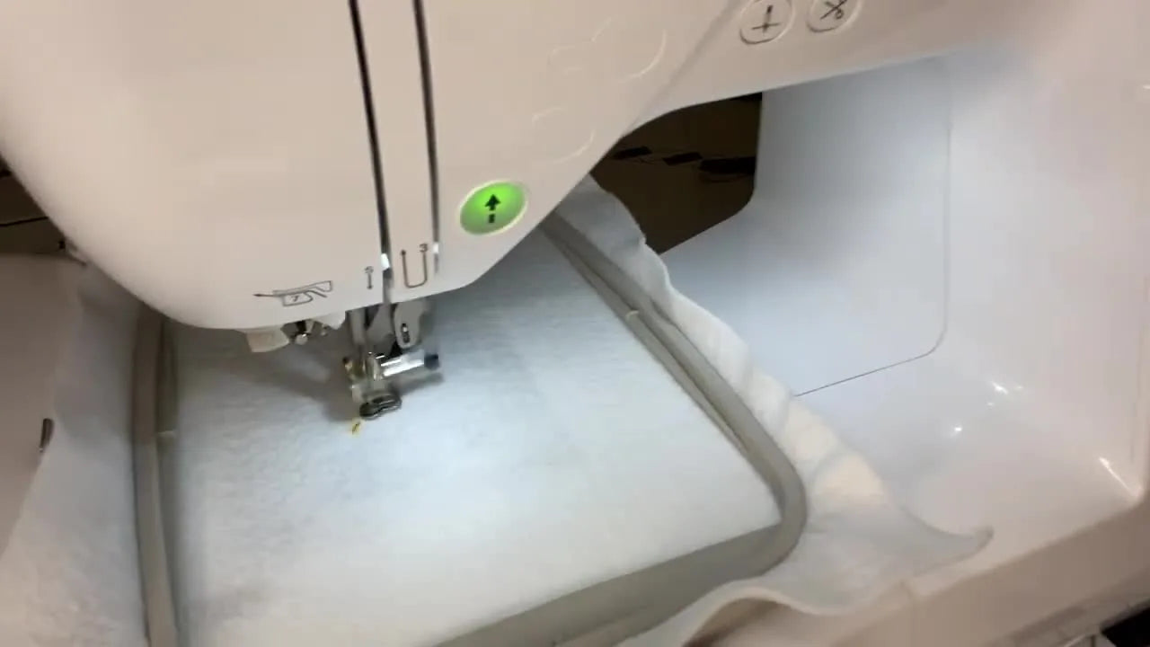 A close-up of the Brother PE800 needle stitching gold thread into white felt inside a 5x7 hoop.