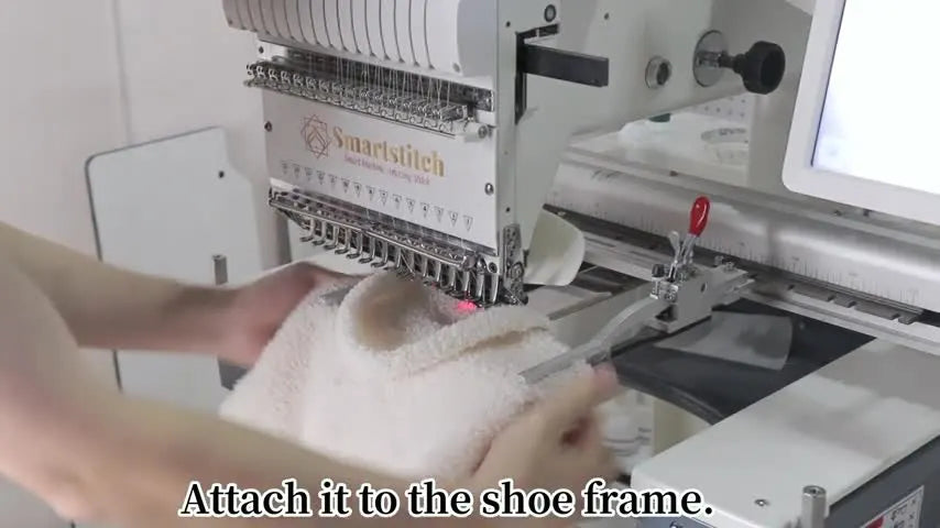 A close view of the SmartStitch multi-needle machine as the red clamp lever locks a fluffy tote bag securely in the shoes frame.