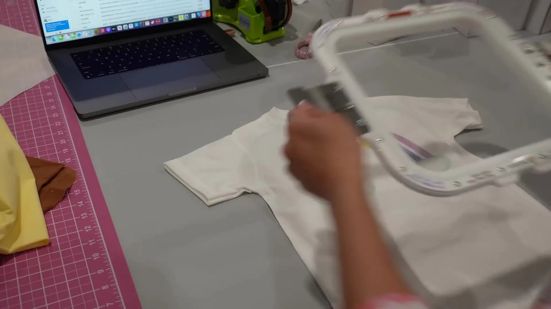 An overhead shot of a magnetic hoop snapping together through a thick polyester T-shirt, ready to embroider over a freshly sublimated rainbow background.