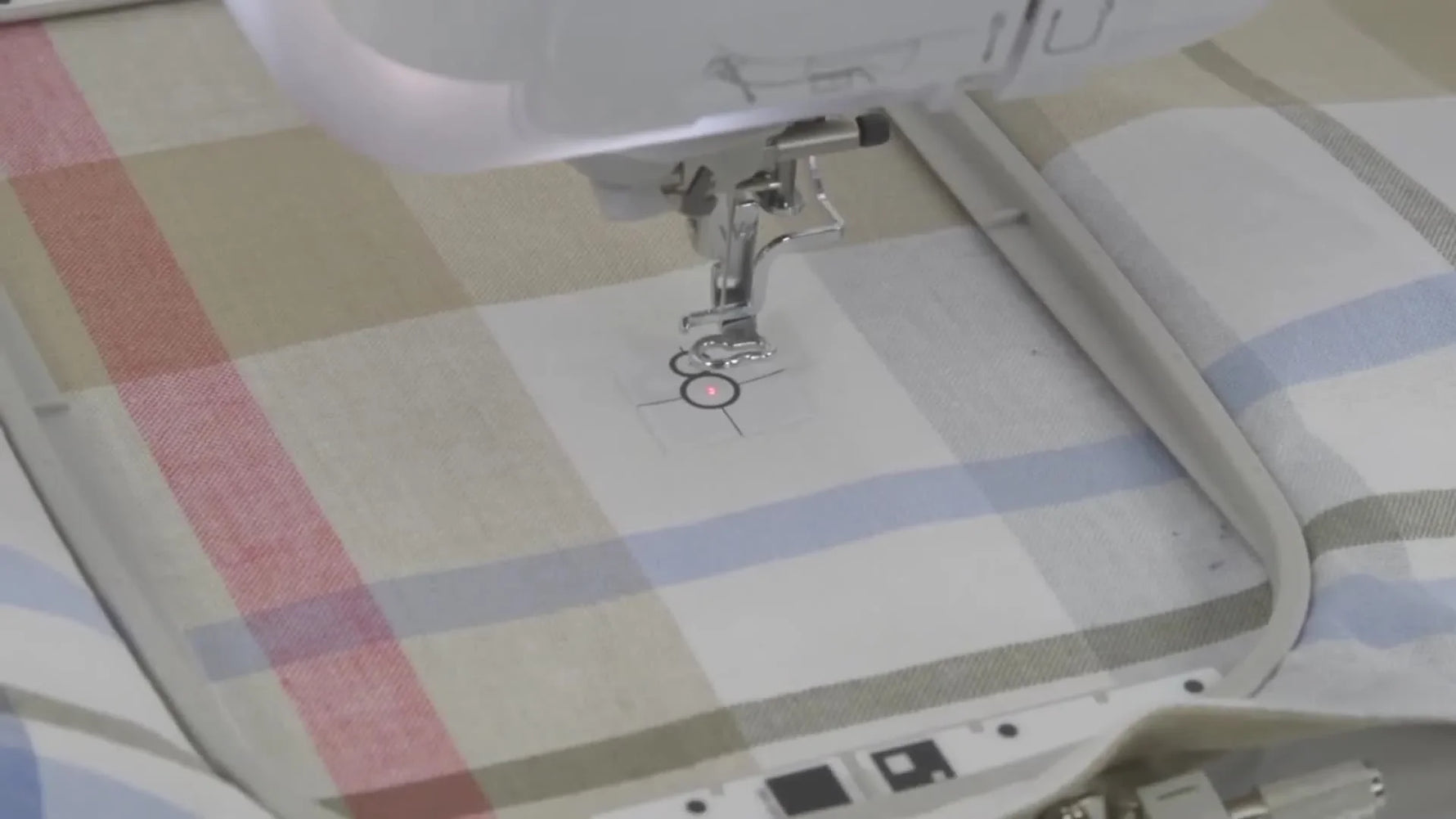A close-up of the Brother Stellaire’s red LED pointer landing precisely on the Snowman sticker’s large center dot for accurate embroidery placement.