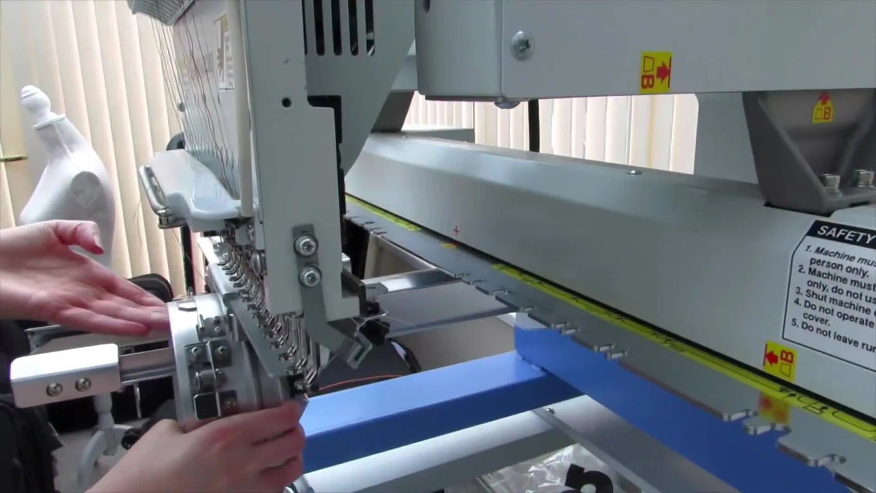 The cap driver being slid onto the centered pantograph arm of the embroidery machine.