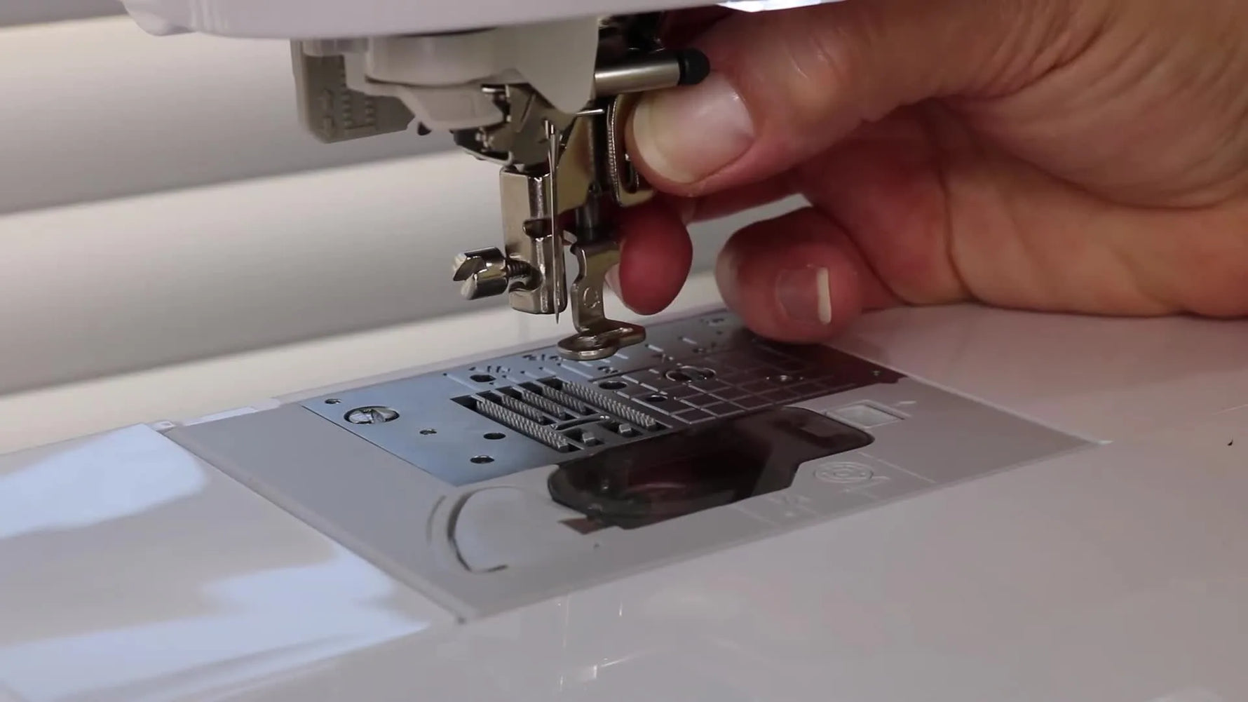 A close-up shows the Brother SE1900 Q embroidery foot correctly positioned with its upper arm sitting over the needle clamp screw.