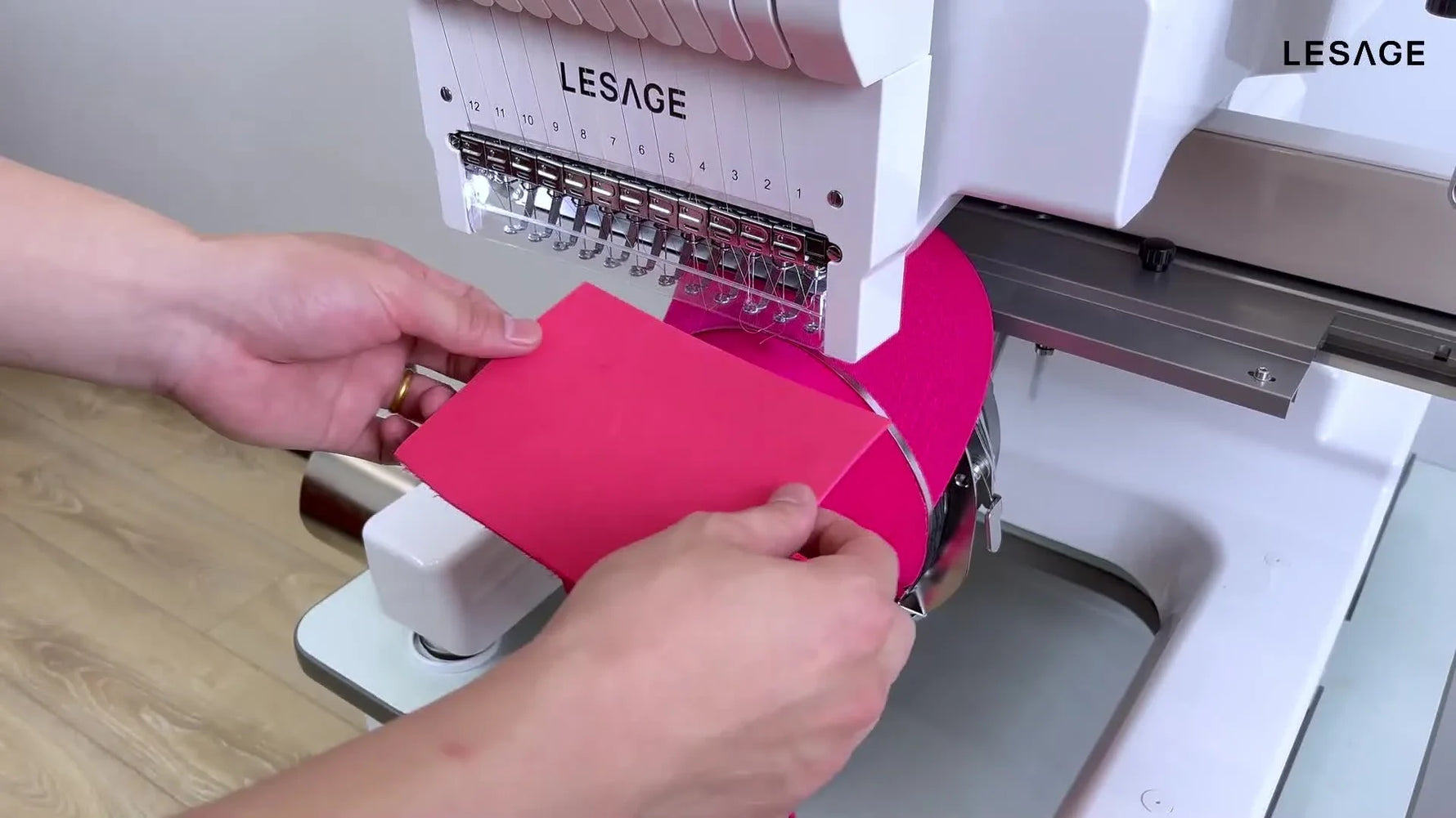 An extreme close-up shows the LESAGE machine stitching through pink foam to create a raised 3D puff letter on a cap.