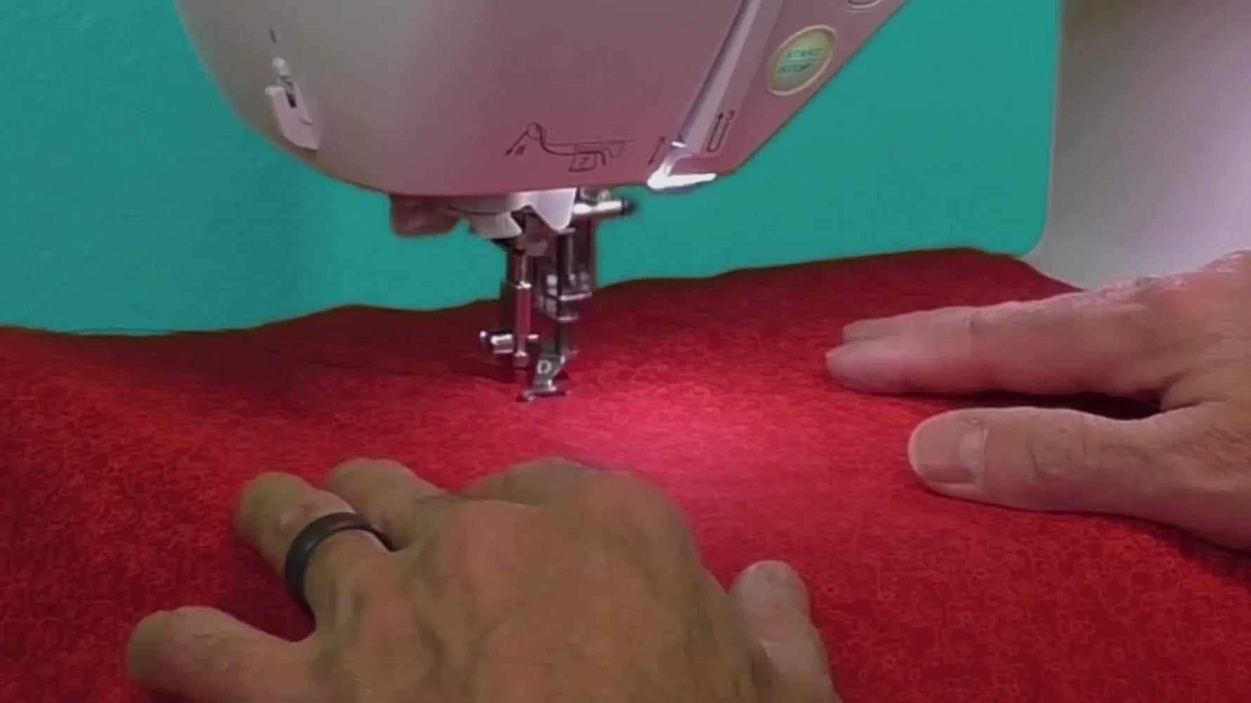 Close-up of the Baby Lock Vesta stitching on red fabric, highlighting the needle area and Baby Lock branding.