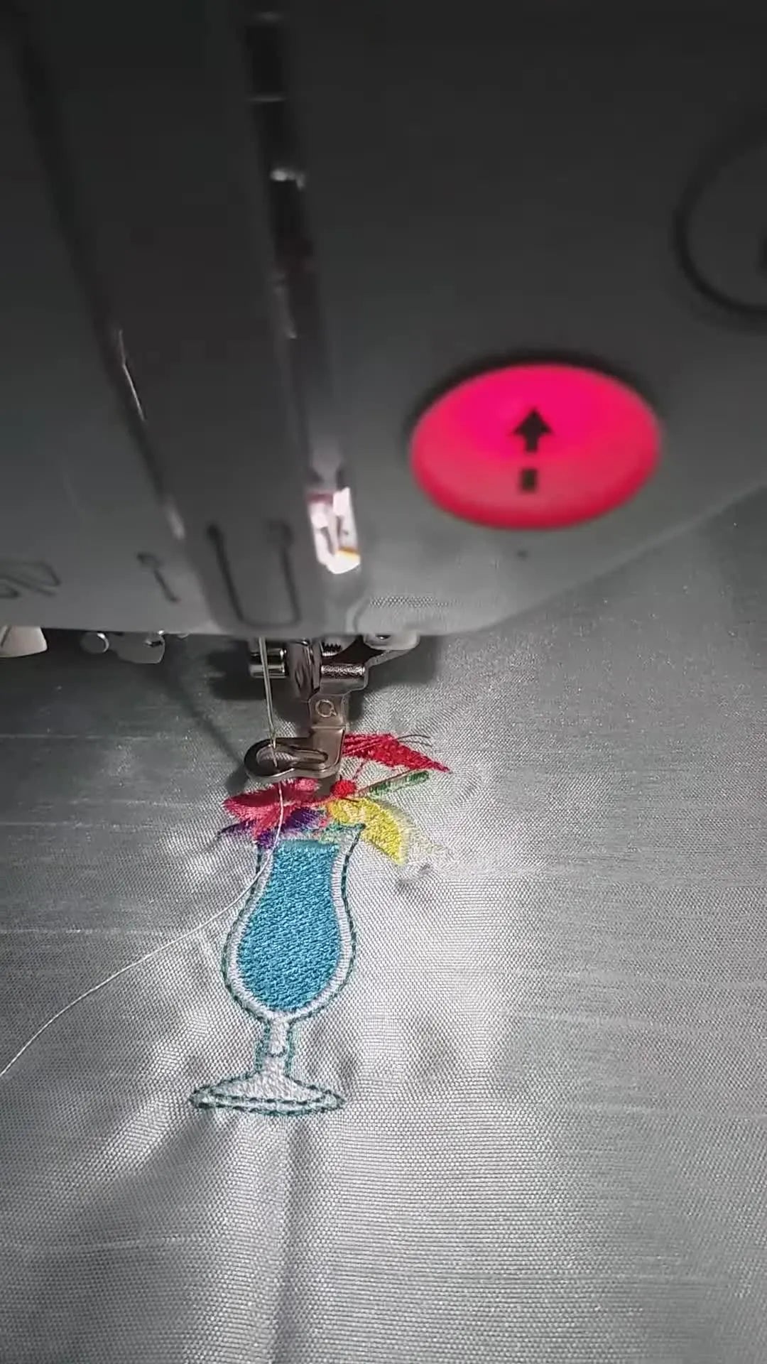 A close-up of the nearly finished cocktail-glass embroidery stitching cleanly on silver handbag lining fabric under the Brother Innov-is F480 presser foot.