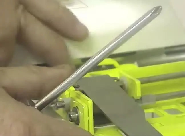 Close-up of the yellow clamp mounted on the machine arm with a screwdriver positioned to gently adjust the metal sensor arm for hoop recognition.