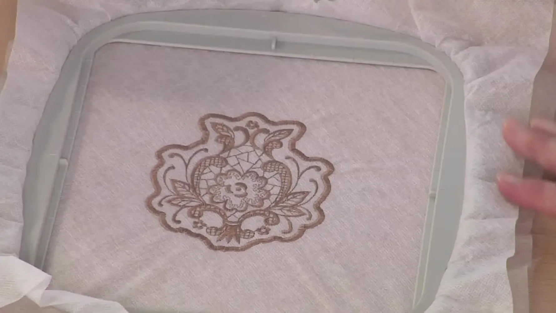 A finished free-standing lace design is shown stitched in the hoop, surrounded by water-soluble stabilizer and ready for trimming and wash-away.