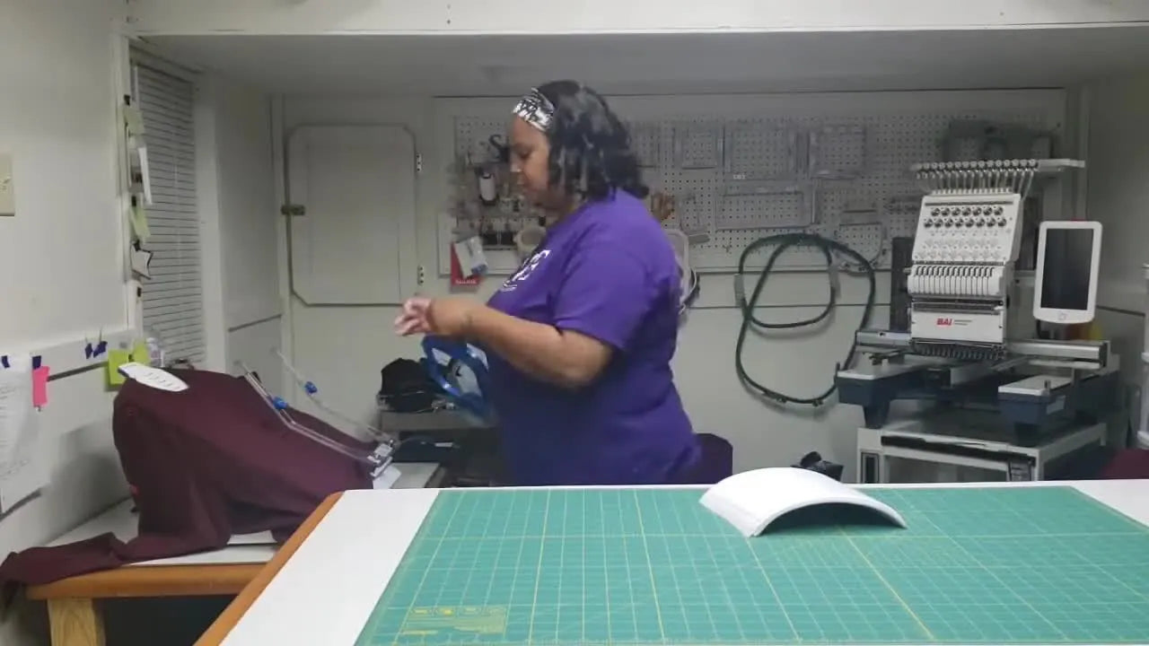 A close view of pressing a 5.5-inch magnetic hoop onto a shirt on the hooping station for consistent placement.