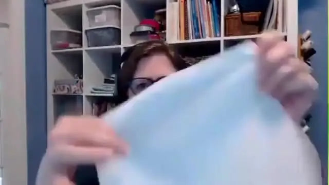 A presenter holds a sheet of opaque white permanent topper film, showing the texture and coverage used to keep white embroidery bright on dark fabrics.