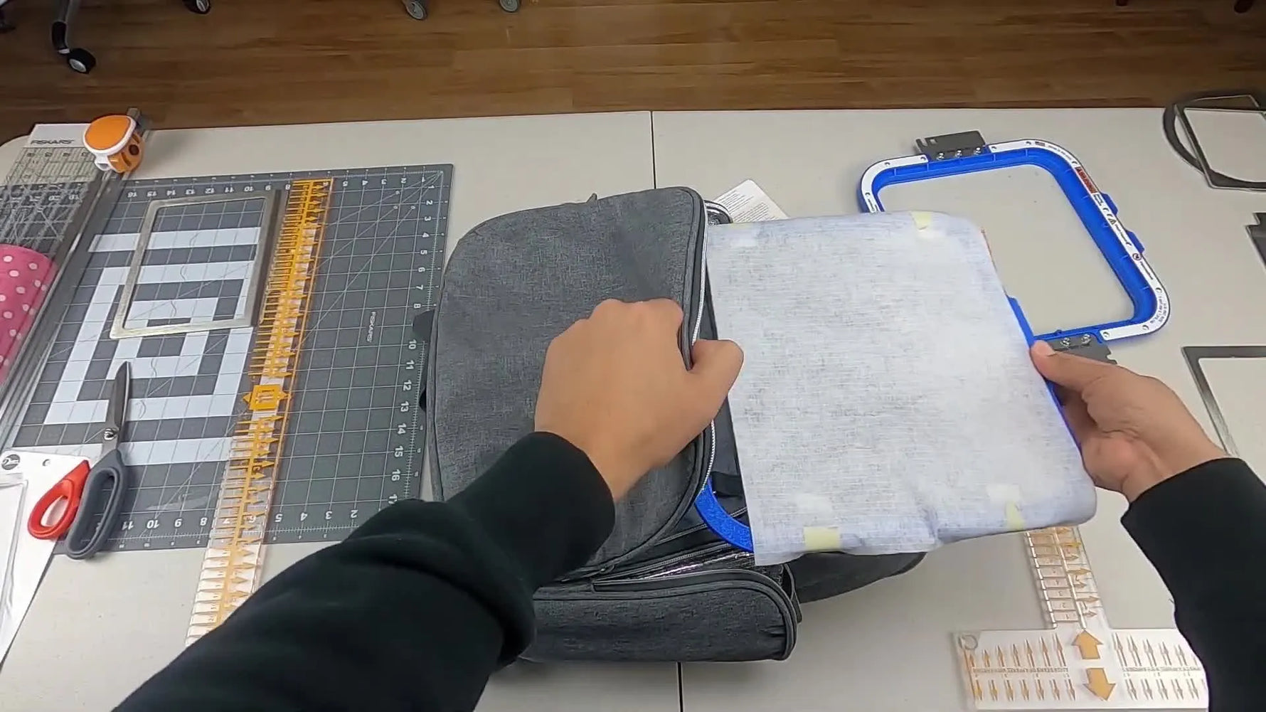 A top-down view shows a magnetic hoop aligned to blue center marks on a thick diaper bag pocket just before it snaps into place.