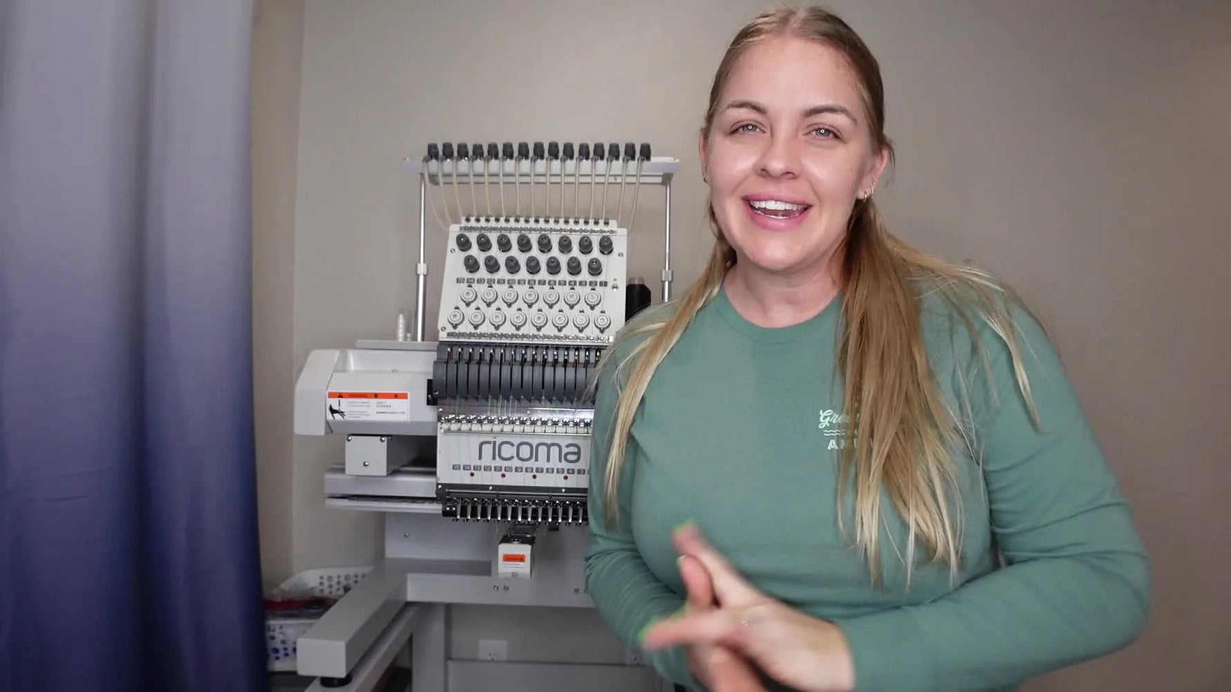 Woman standing in front of Ricoma embroidery machine, smiling at camera