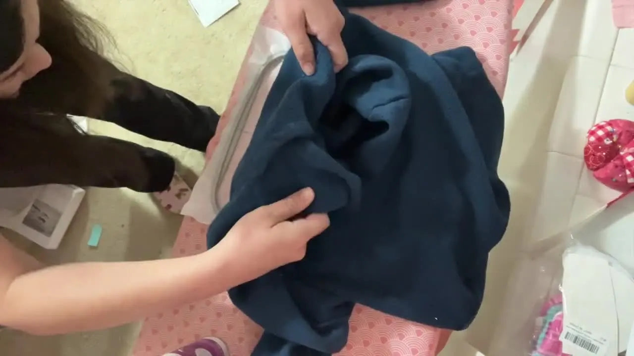 Hands press an inside-out fleece sweatshirt onto sticky hooped stabilizer, demonstrating the floating technique for clean placement without hoop burn.