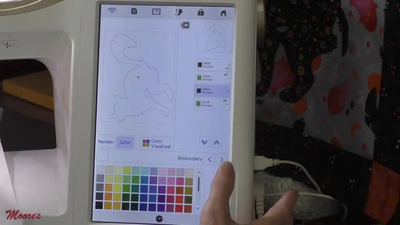 The machine screen highlights the Appliqué Material icon in the color palette, the key step that turns your outline into ScanNCut cut data.