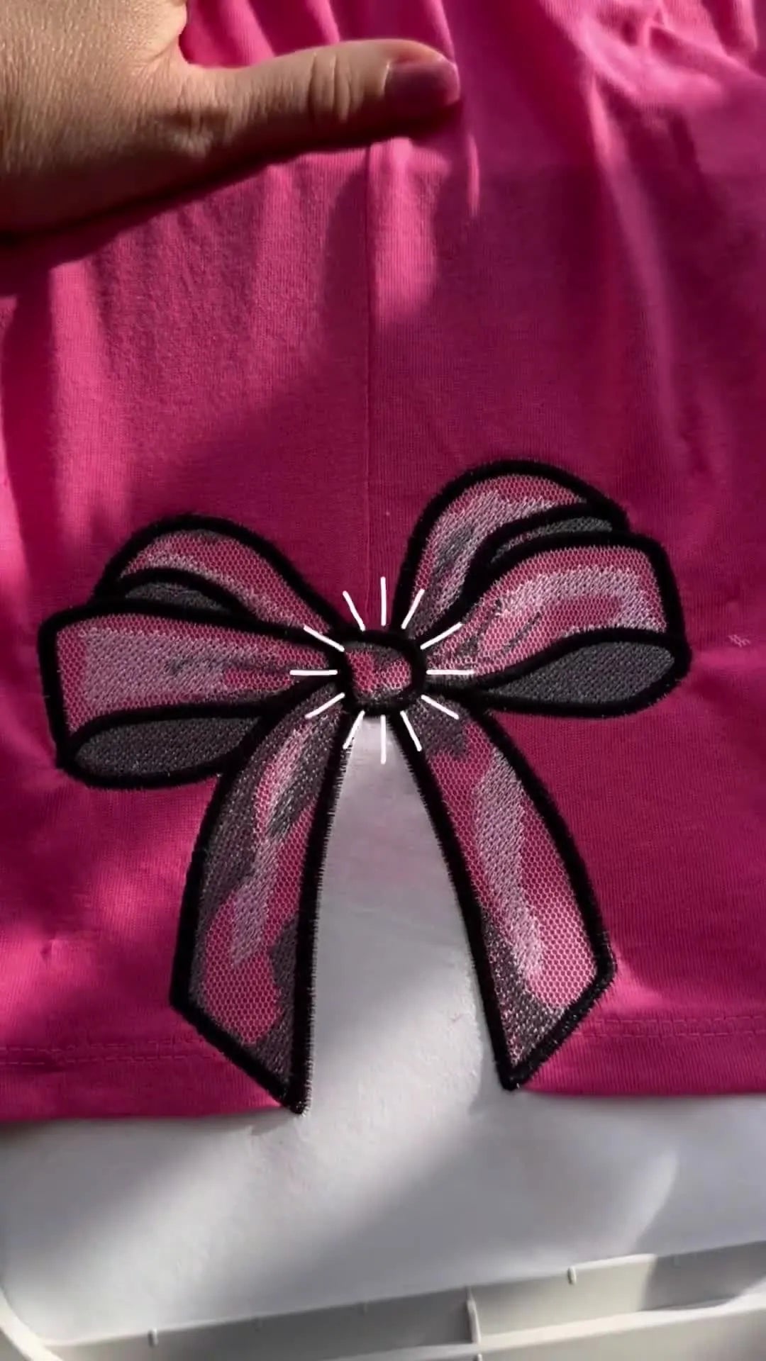 The finished cutwork bow embroidery is shown in the hoop, with the mesh revealing a clean see-through effect inside the bow loops.