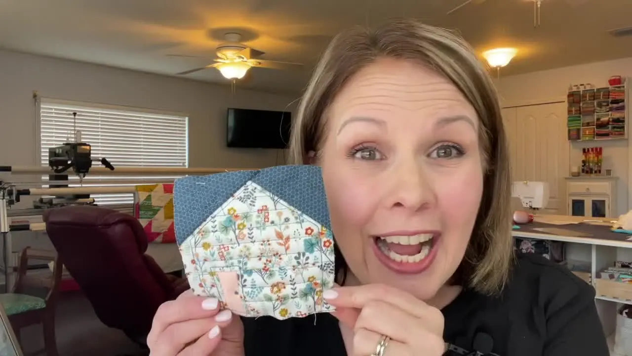 A close-up of the finished in-the-hoop house quilt block showing crisp piecing and blue quilting details.