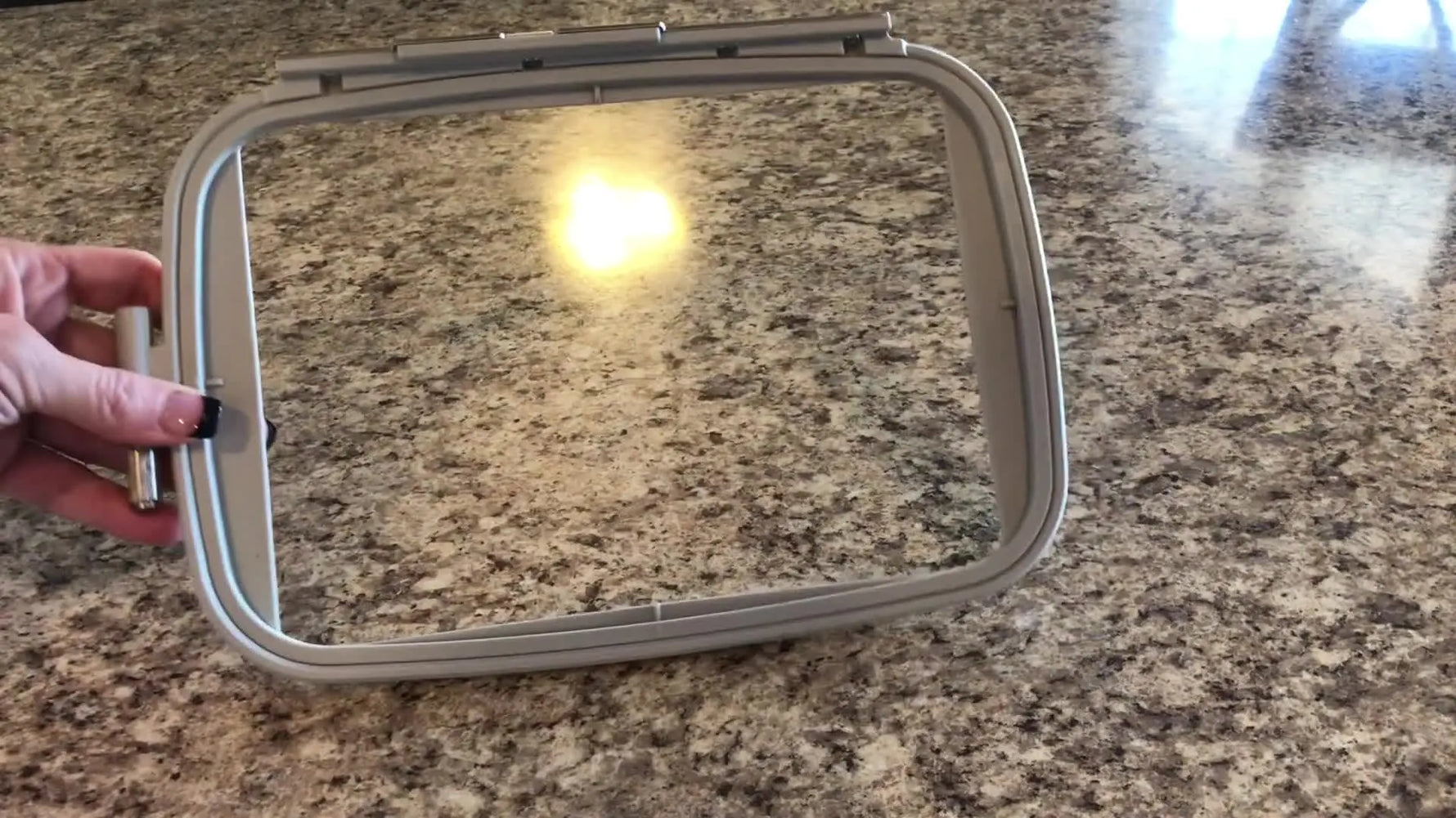 A completely clean embroidery hoop is held up after the adhesive residue has been removed.