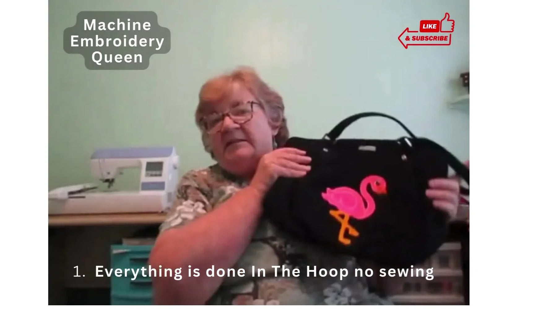 Mary holds up a finished black tote bag with a pink flamingo appliqué to show the “tear out and done” promise of ITH embroidery.