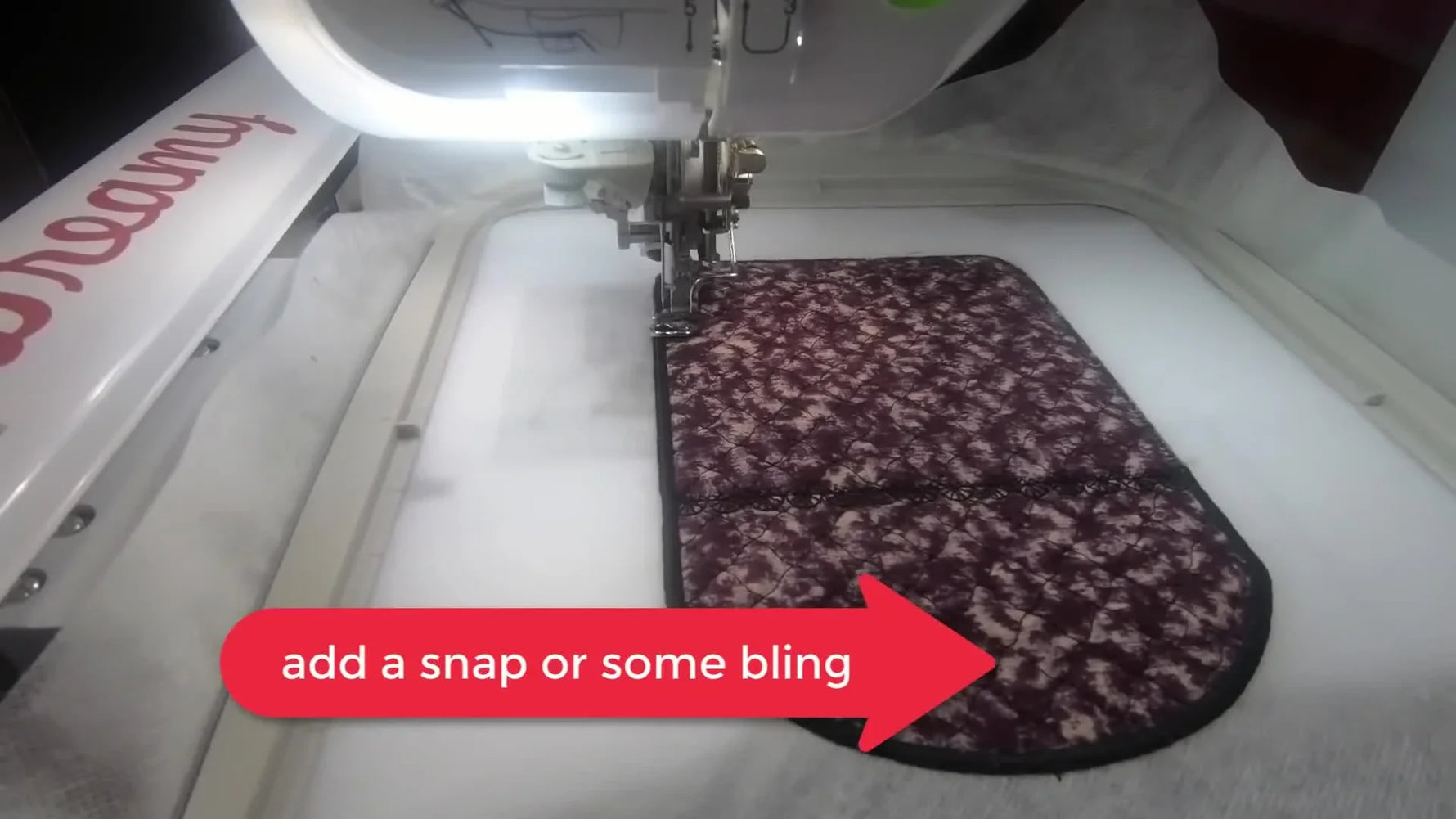 A wide view of the quilted bag finishing its final satin stitches in the hoop on a Brother Dream Machine.