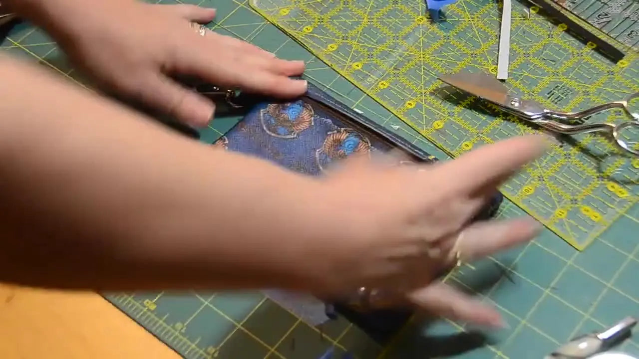 The finished Ravenclaw in-the-hoop zipper bag lies flat on a cutting mat, showing crisp edges, a clean zipper top, and a professional final shape.