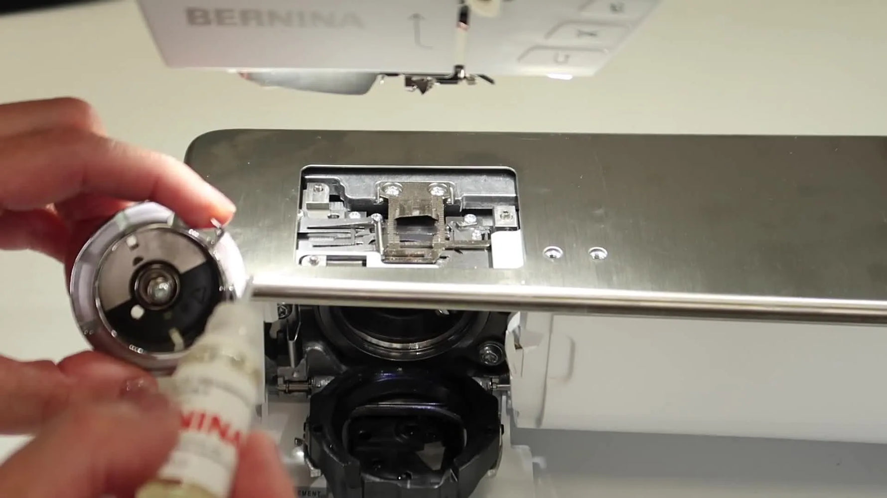 A close-up macro shot shows a precise drop of oil being applied to the Bernina 790 PRO hook’s internal felt reservoir pad.