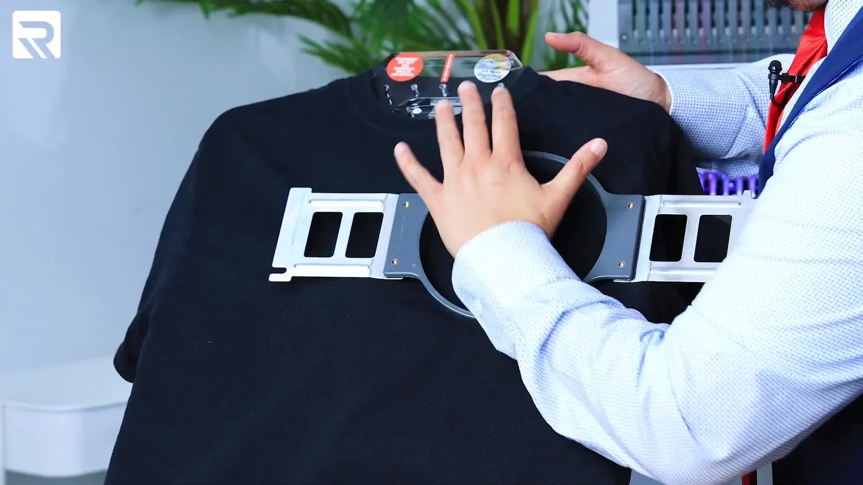Close-up of pressing a magnetic top hoop down onto a black T-shirt on a hooping station for fast, repeatable left-chest placement.