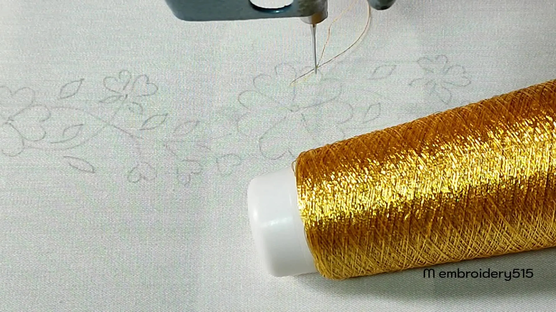 Embroidery machine needle poised above a fabric with a golden thread spool