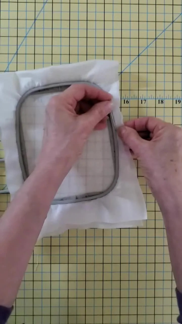 A close-up shows a 2-inch T-pin inserted through mesh water-soluble stabilizer right against the inner frame of a Brother-style plastic hoop to prevent stabilizer slippage.