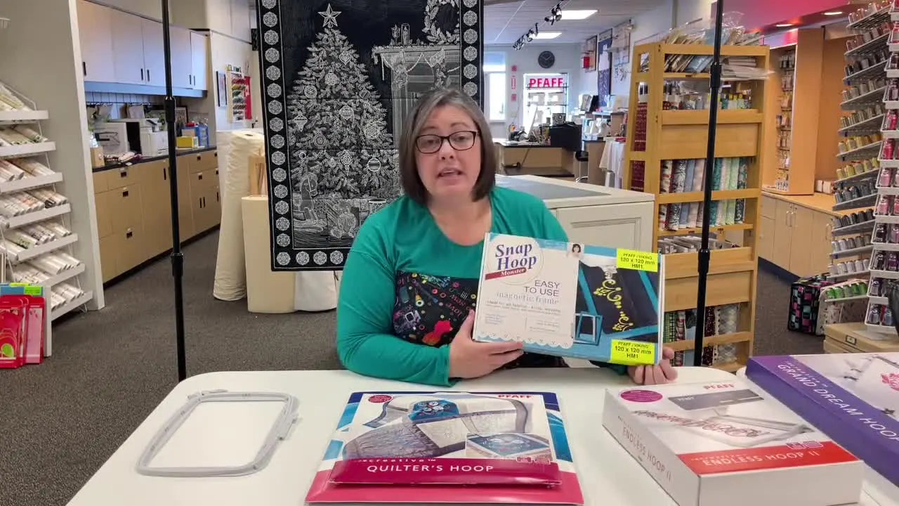 Nichole holds up the Snap Hoop magnetic frame packaging, highlighting it as the easiest way to hoop thick or mark-prone materials.