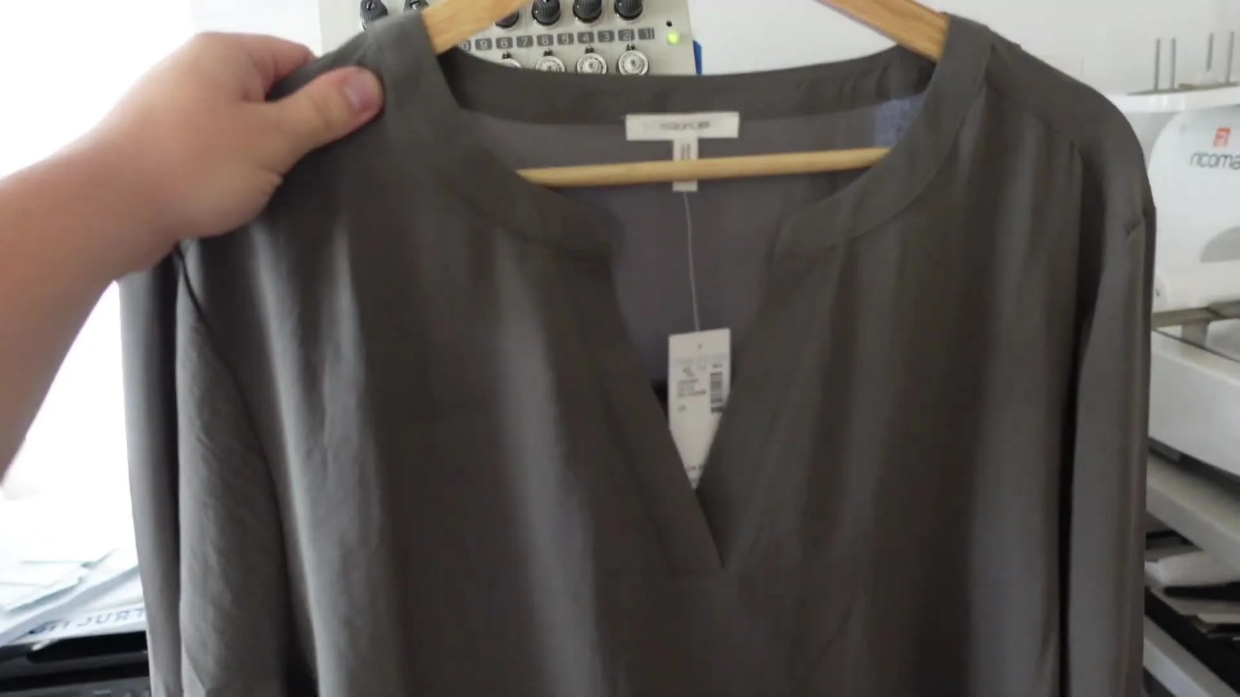 Woman holding a thin gray blouse provided by an insurance agency.