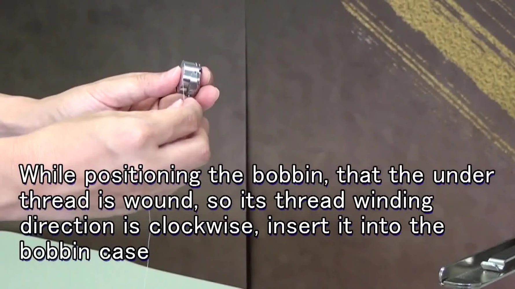 Hand guiding under thread through slit in bobbin case