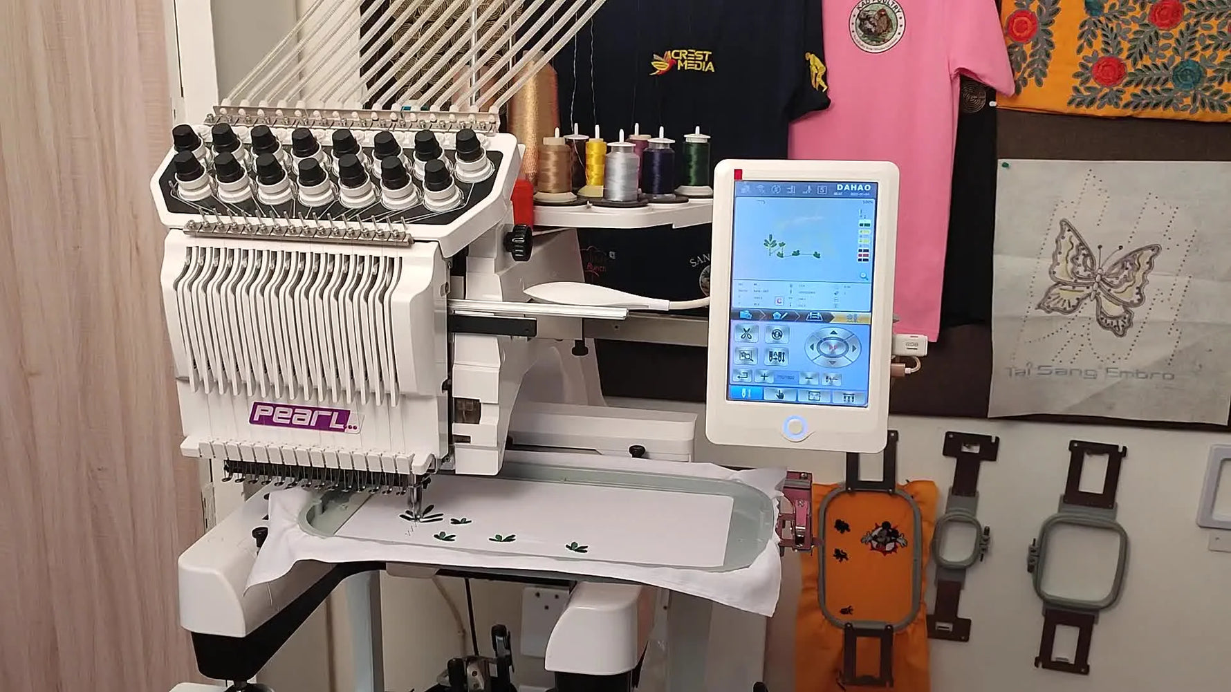 A wide view of a Pearl multi-needle embroidery machine with a lit DAHAO touchscreen moments before stitching begins.
