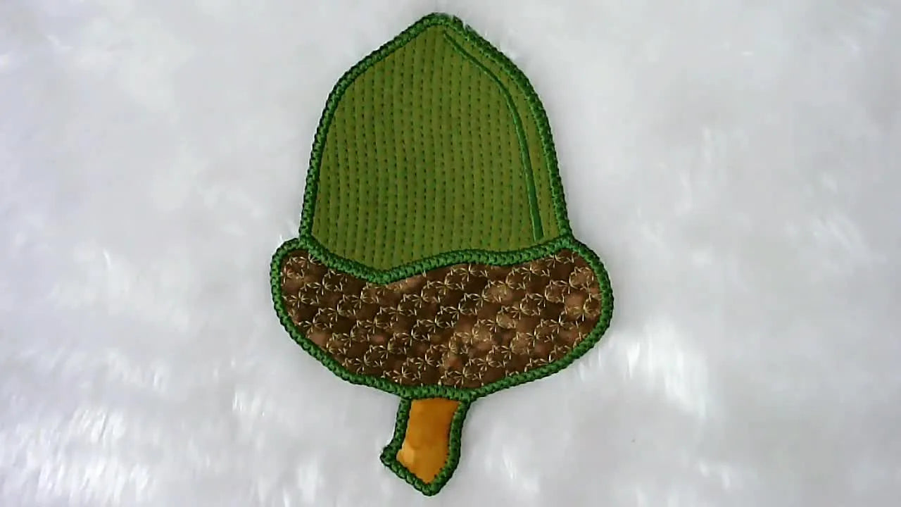 A finished reversible acorn placemat with a clean satin border is displayed on a white fur background.