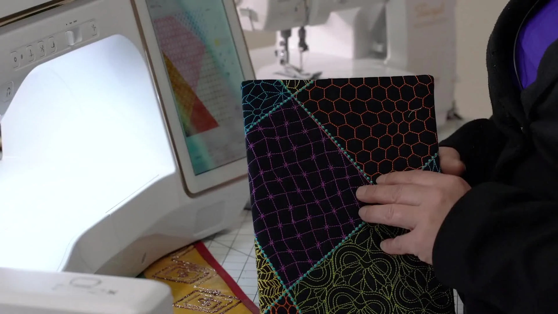 A close-up of neon geometric fill stitches on black fabric, showing how dense fills and warping can create a pebble-like quilting texture.