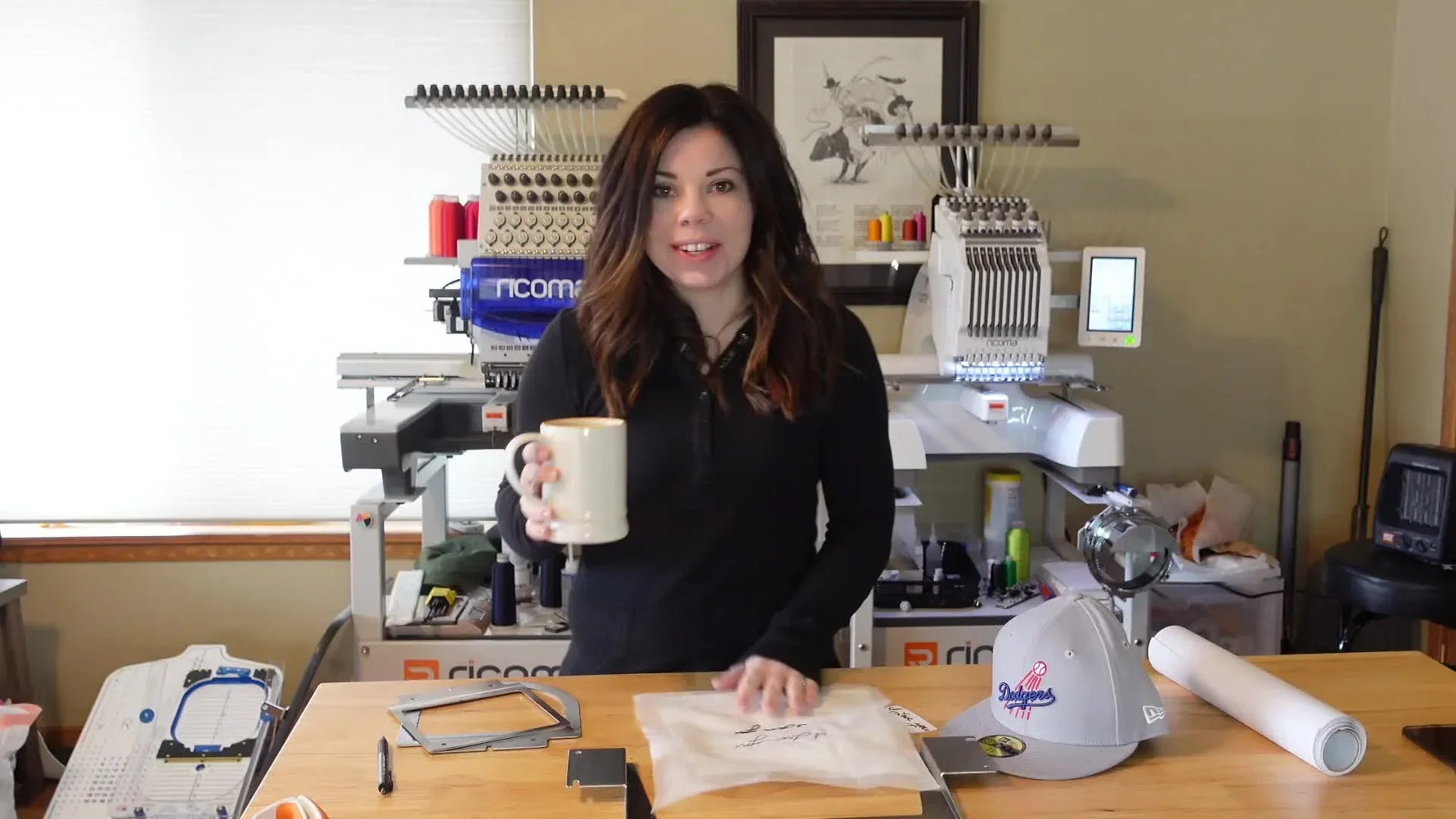 Presenter in front of Ricoma EM-1010, ready to embroider a hat.