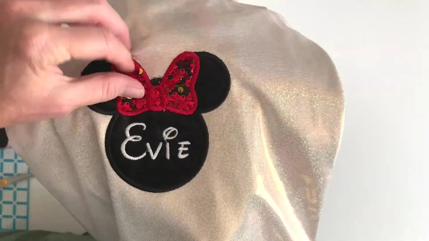A close-up of the finished Minnie-style bow as a finger flips the reversible sequins to reveal the interactive color change.