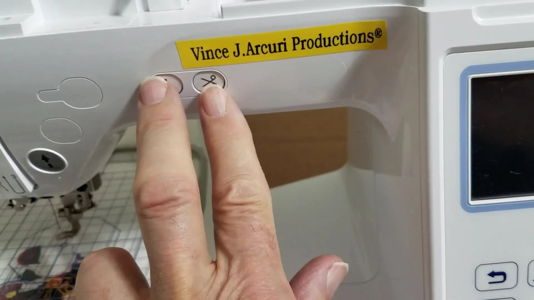 Close-up of two fingers holding the Needle Up/Down and Thread Cutter buttons on a Brother PE800 to boot into the hidden service menu.