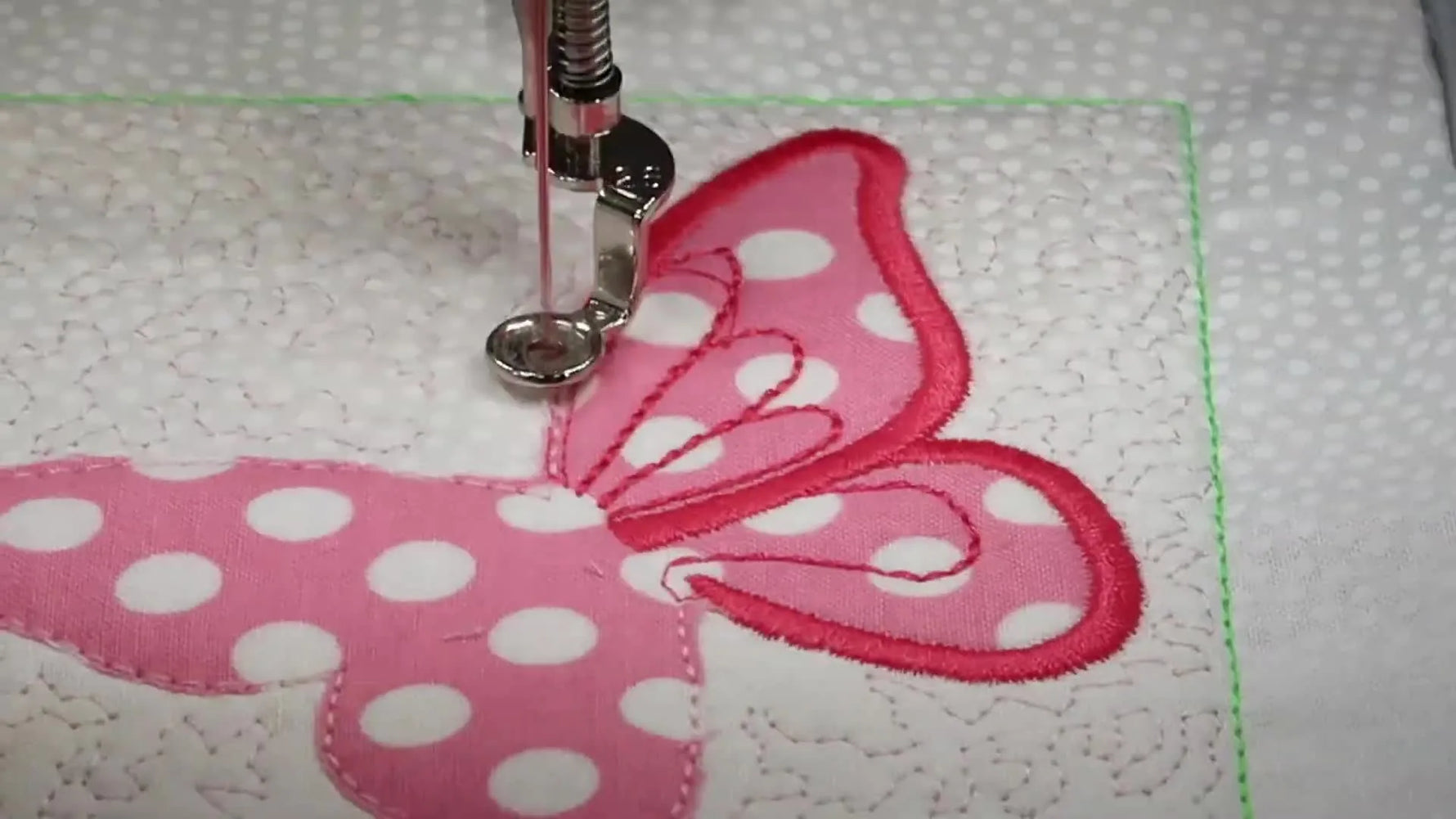 A finished butterfly appliqué quilt block with stippled quilting and a clean satin-stitched edge, shown flat and centered in the frame.