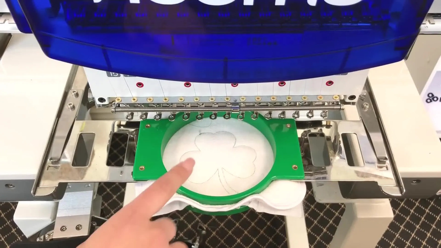 The embroidery frame is offset forward on the Ricoma machine, creating safe working space to place the appliqué fabric precisely inside the stitched outline.