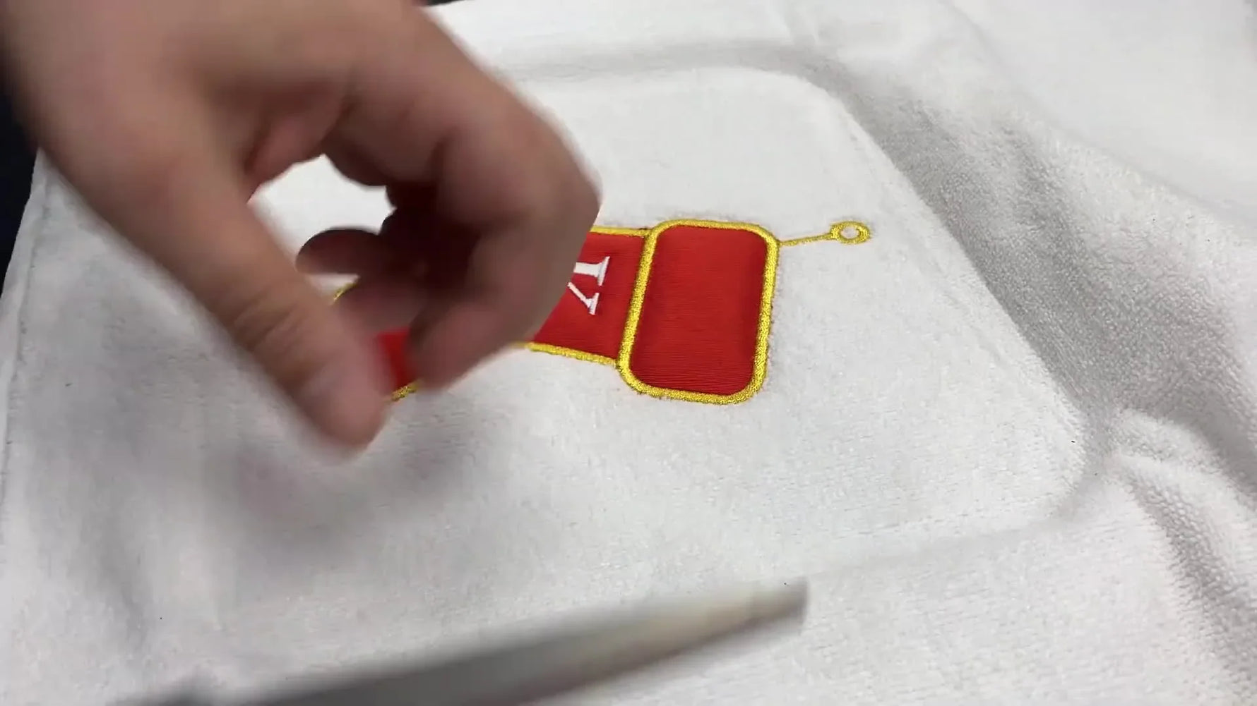 A completed holiday stocking appliqué stitched on a white microfiber towel is held up in front of the Avancé 1501 machine.