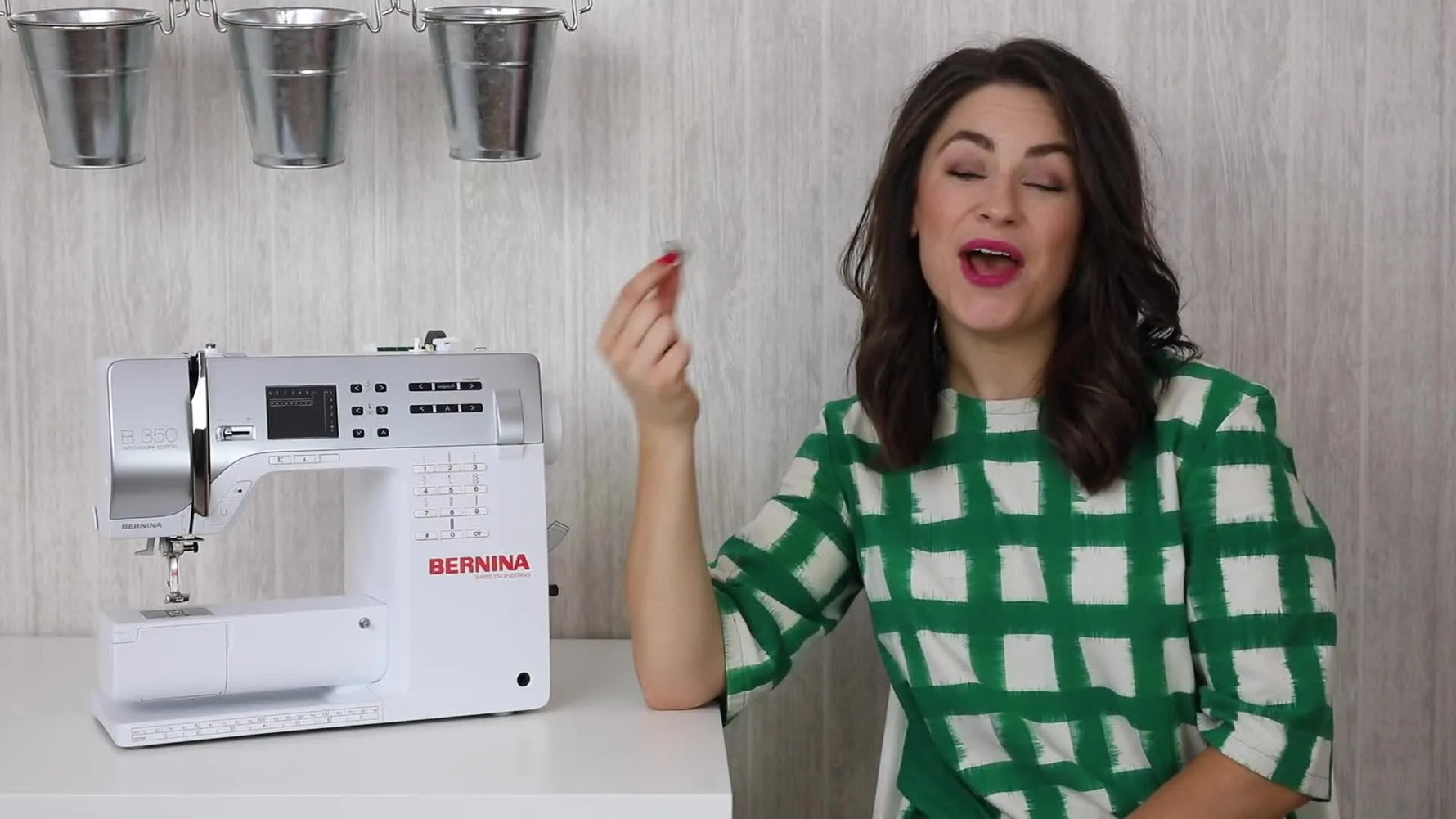 Woman holding a perfectly wound bobbin in front of a sewing machine.