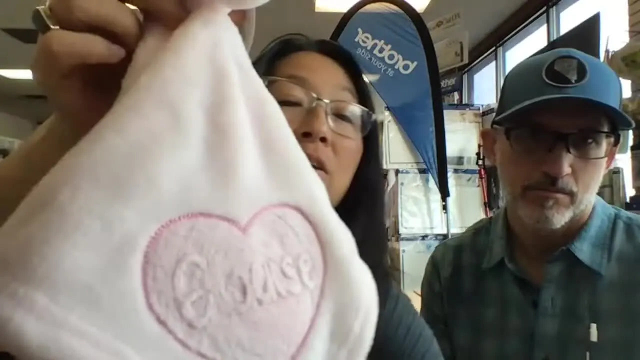 Close-up of a pink plush baby blanket showing a heart design and the name “Eloise,” with the knockdown stitch texture visible under the lettering.